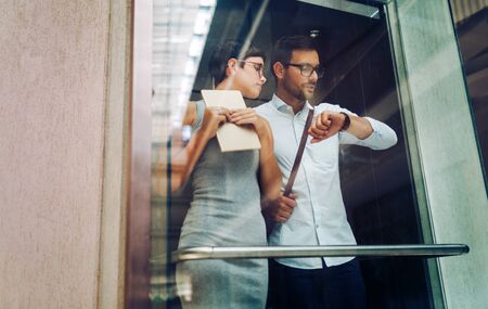 Picture of young businesspeople talking in elevatorの写真素材
