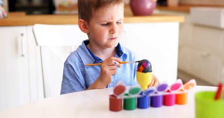 Cute little boy painting easter eggsの写真素材