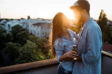 Happy couple enjoying drinks and balconyの写真素材