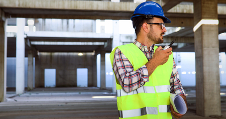 Architect holding rolled up blueprints at construction site