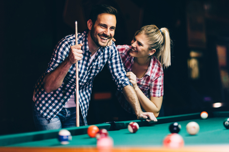 Young couple playing snooker together in barの写真素材