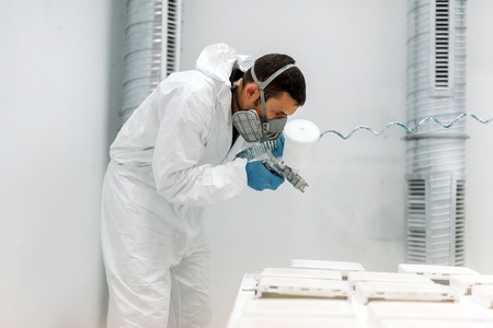 Painter using airbrush to paint wearing protective clothingの写真素材