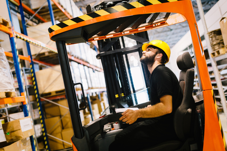 Warehouse worker doing logistics work with forklift loaderの写真素材