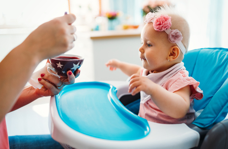 Portrait Of Happy Young Baby In High Chair being fedの写真素材