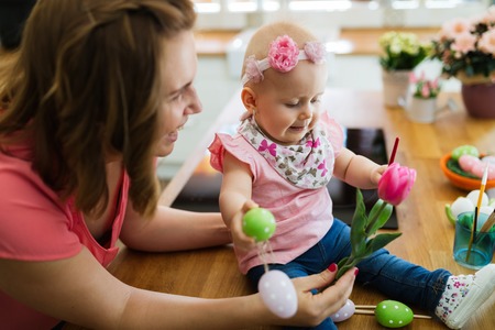 Happy mother and baby making decoration with bouquet of tulips