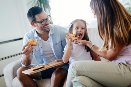 Happy family sharing pizza together at homeの写真素材