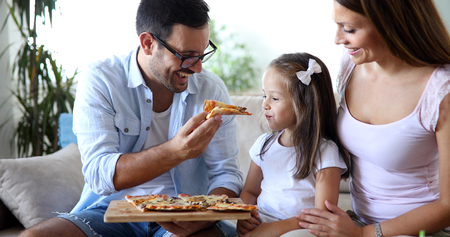 Happy family sharing pizza together at homeの写真素材