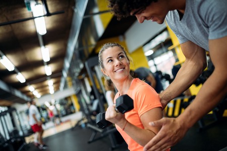Young beautiful woman doing exercises with personal trainerの写真素材