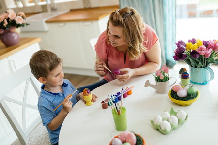 Mother and her son having fun decorate eggsの写真素材