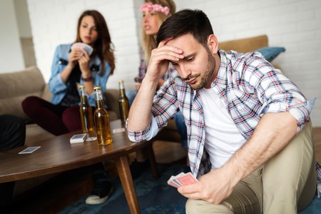 Happy group of friends playing cards and drinkingの写真素材