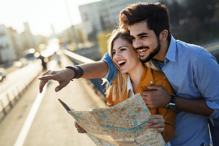 Happy tourist couple with map traveling outdoorsの写真素材