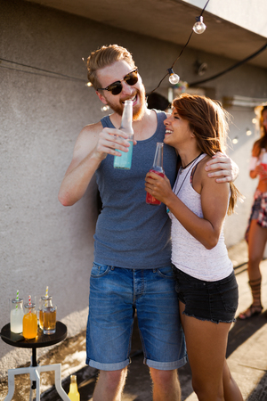 Happy young couple drinking cocktail on rooftopの写真素材