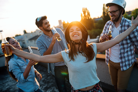 Friends having fun and drinking bgeer outdoor on a rooftopの写真素材