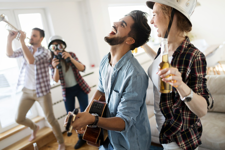 Cheerful friends having party together and playing instrumentsの写真素材