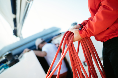 Young handsome sailor pulling rope on sailboatの写真素材