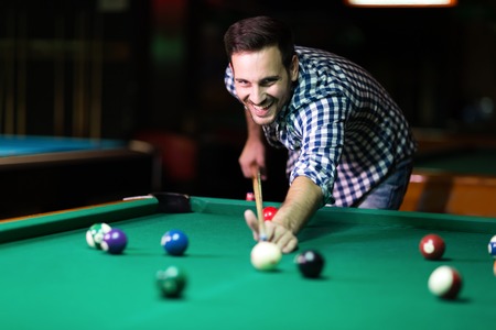 Young attractive man playing pool in barの写真素材