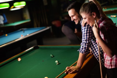 Young couple playing snooker together in bar