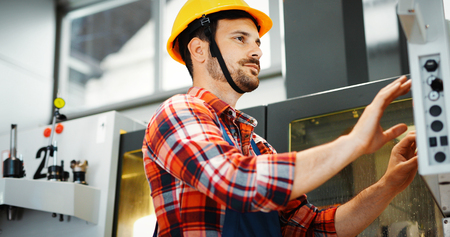 Industry Worker entering data in CNC machine at factory