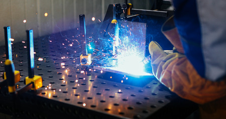 Metal worker welding with torch in metal industry factory