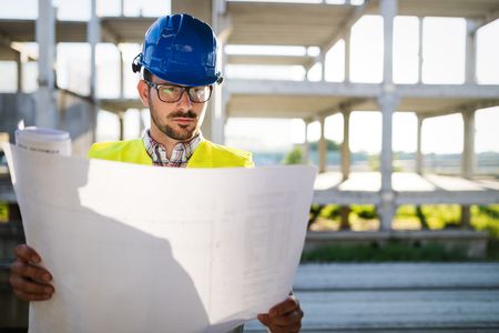 Construction engineer in hardhat with project in hands