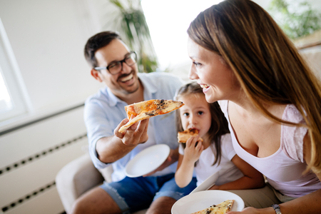 Happy family sharing pizza together at homeの写真素材