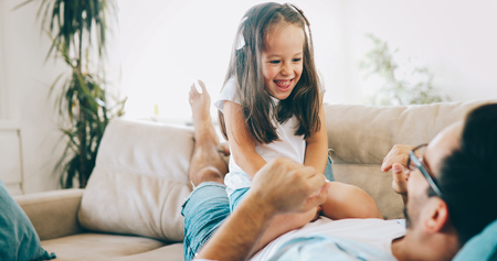 Portrait of father and daughter playing at homeの写真素材