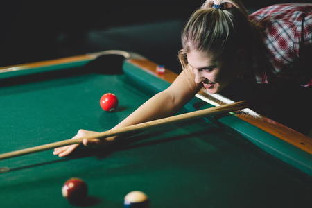 Young attractive woman playing pool in bar