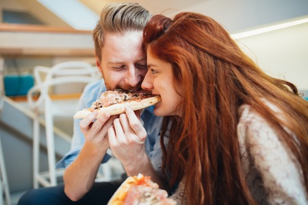 Couple sharing pizza and eatingの写真素材