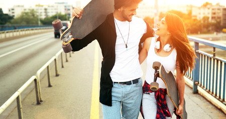 Young attractive couple riding skateboards and having funの写真素材