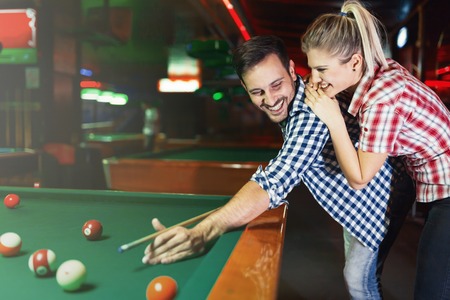 Young couple playing together pool in bar