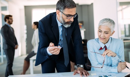 Happy mature businessman and businesswoman planning in office