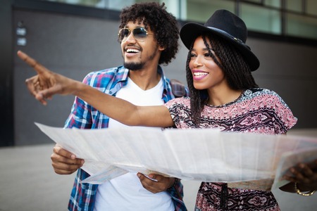Happy young black couple of travellers holding map in hands