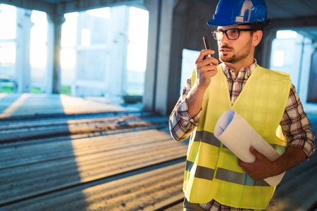 Architect holding rolled up blueprints at construction siteの写真素材
