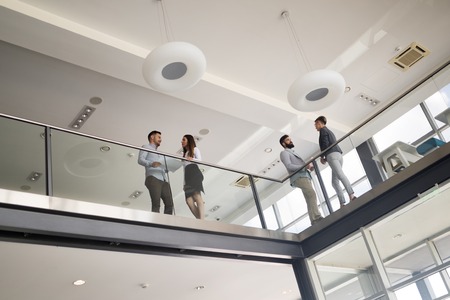 Modern business people walking on stairs in glass hall in office