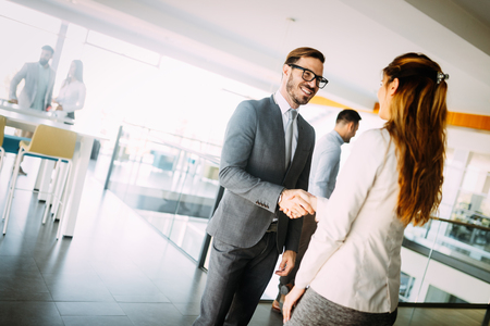 Young businessman and woman shake hands as hello in office portraitの写真素材
