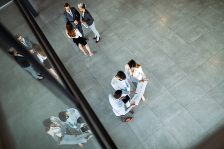 Modern business people walking on stairs in glass hall in officeの写真素材