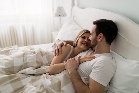 Young attractive couple having romantic time in bedの写真素材