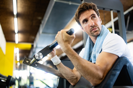 Handsome happy fit man doing exercises in gym