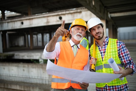 Engineer, foreman and worker discussing in building construction siteの写真素材