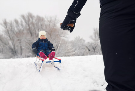 Little girl enjoying a sleigh ride. Child sledding. Toddler kid riding a sledge.