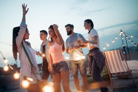 Carefree group of happy friends enjoying party on rooftop terrace