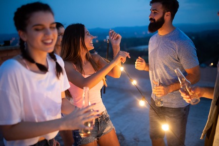 Carefree group of happy friends enjoying party on rooftop terraceの写真素材