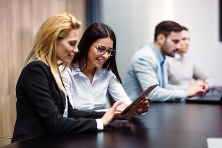 Portrait of two attractive businesswomen using tablet in officeの写真素材