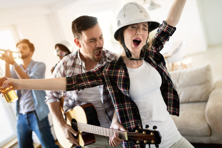 Group of friends playing guitar and partying at homeの写真素材
