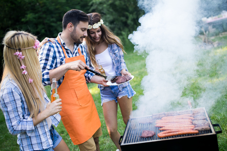 Group of friends making a barbecue together outdoors in the natureの写真素材