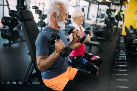 Happy senior people doing exercises in gym to stay fitの写真素材