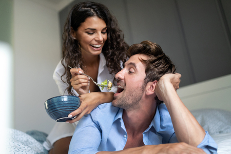 Romantic happy couple having breakfast in bedの写真素材