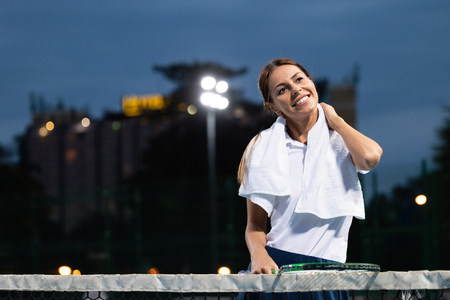 Woman tennis player with injury holding the racket on a tennis courtの写真素材