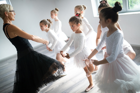 Ballet teacher and group of children ballerinas exercising in ballet studioの写真素材