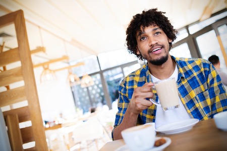Portrait of handsome young african man relaxing with a cup of coffee in cafeの写真素材